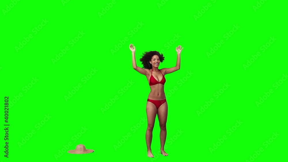 A woman in a bikini has her hat blown off A woman in a bikini has her hat blown off