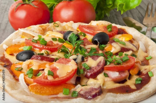 pizza with tomatoes, cheese, black olives and peppers.