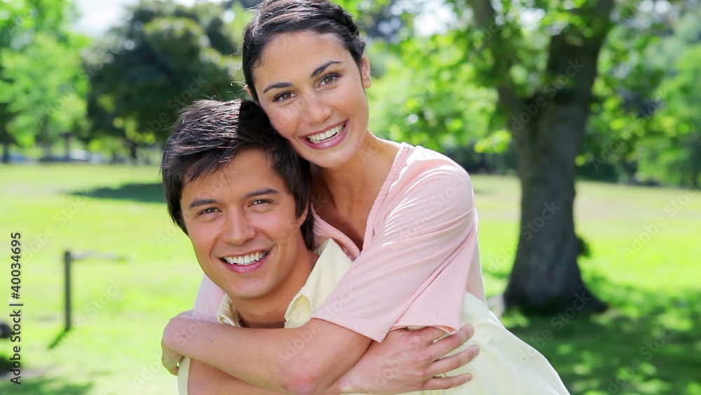 Smiling man giving her girlfriend a piggy-back Smiling man giving her girlfriend a piggy-back