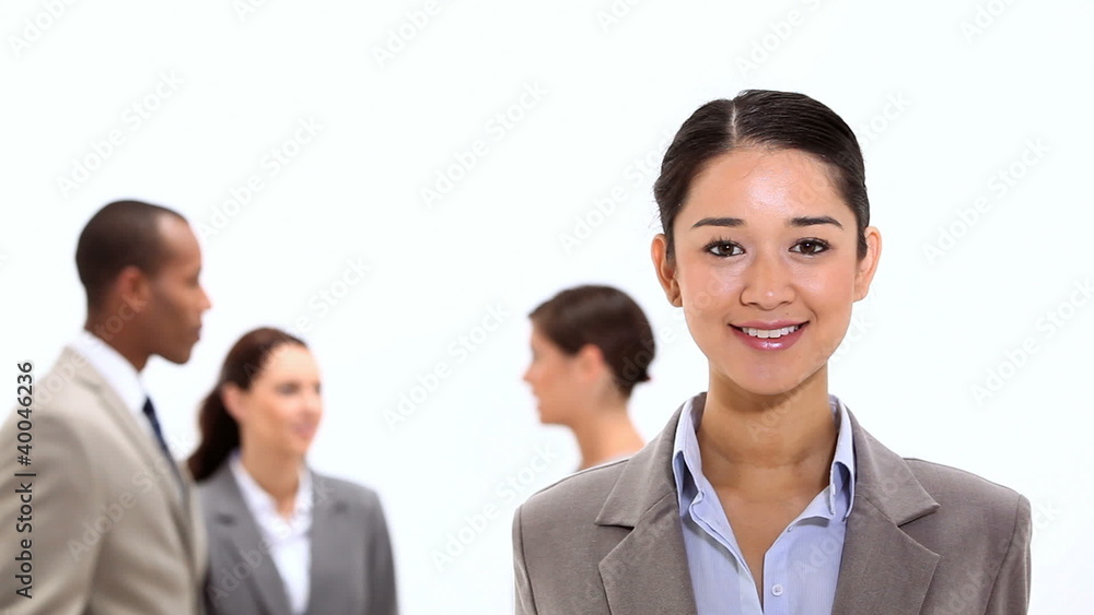 Smiling businesswoman with co-workers behind her Smiling businesswoman with co-workers behind her