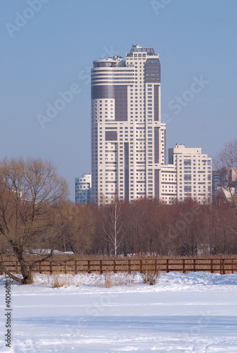 Winter landscape with modern high building after forest