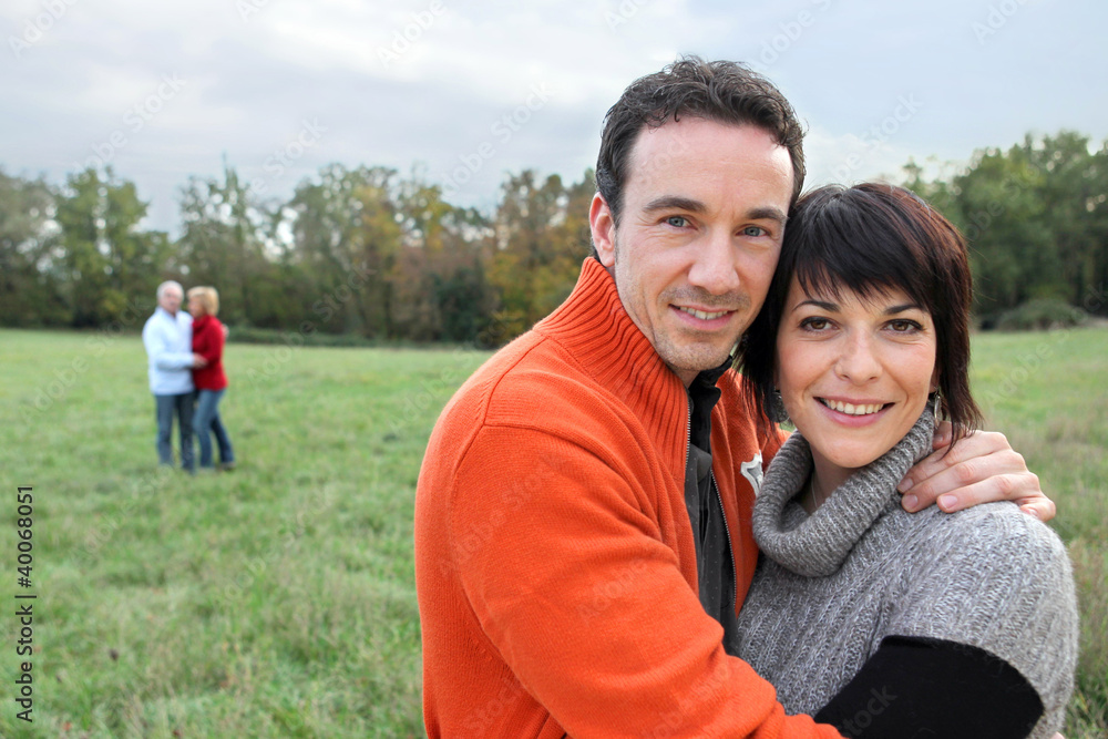 Two generations on couples stood in field Two generations on couples stood in field