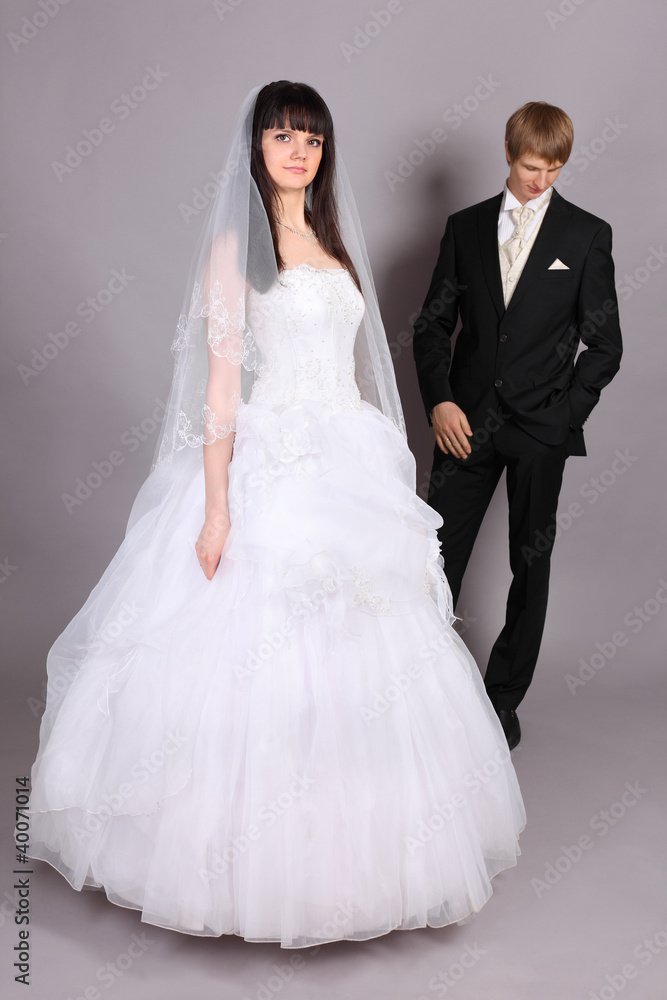 Beautiful bride stands in studio on gray background