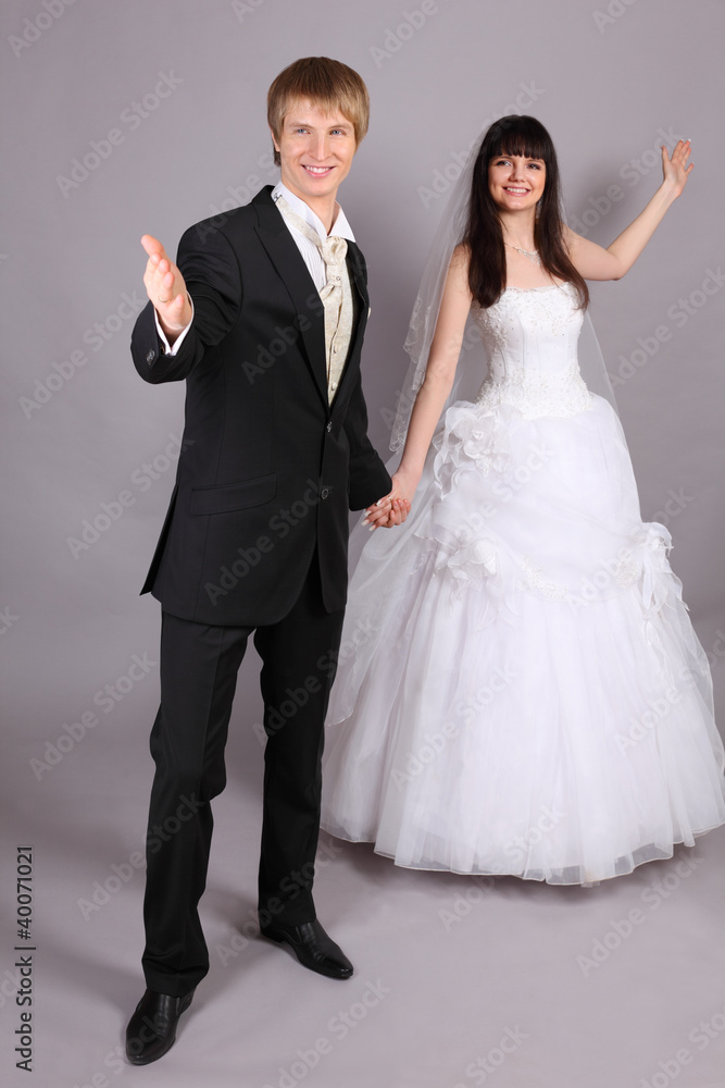 Beautiful bride and groom welcome in studio on gray background Beautiful bride and groom welcome in studio on gray background