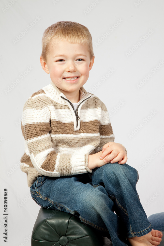 blond boy sitting on a bench smiling at the camera blond boy sitting on a bench smiling at the camera