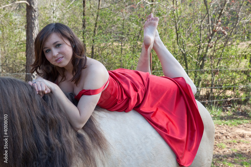 Canvas Print Woman in red dress riding a horse bareback