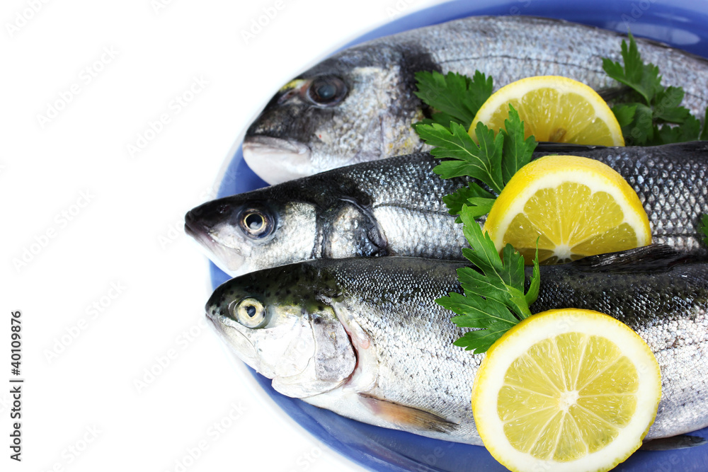 Fresh fishes with lemon and parsley on plate isolated on white Fresh fishes with lemon and parsley on plate isolated on white