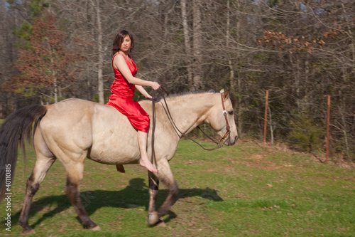 Woman in a red dress, riding a horse bareback