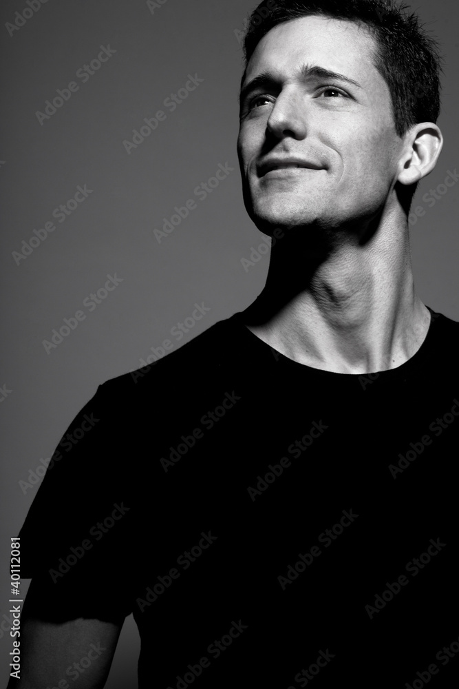 Man in black t-shirt posing on gray background.