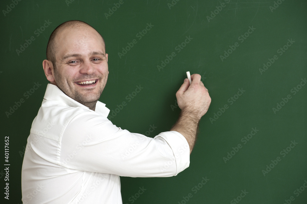 Lächelnder Lehrer schreibt an die Tafel.