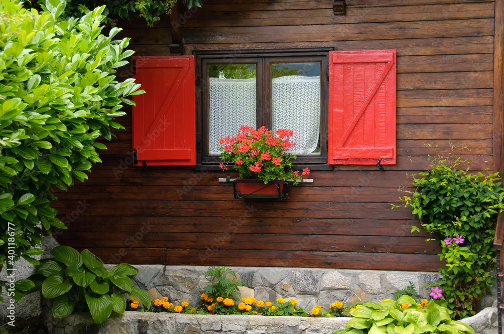 Foto Stock piccola casa di legno con finestre rosse | Adobe Stock