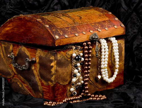 Vintage wooden treasure trunk with jewelry on black background
