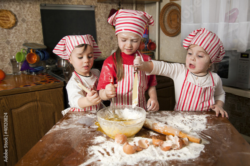 Three little chefs enjoying in the kitchen making big mess. Litt