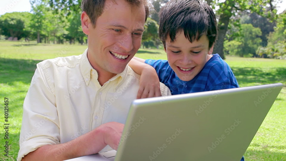 Smiling man using a laptop with his son Smiling man using a laptop with his son