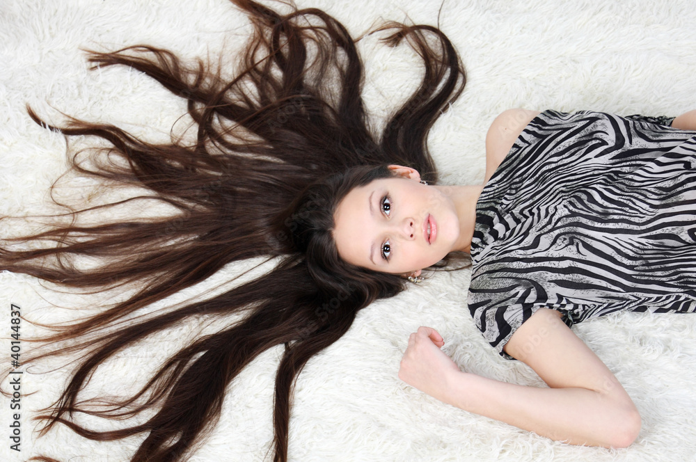young girl with long hair wearing striped dress lies on fur young girl with long hair wearing striped dress lies on fur