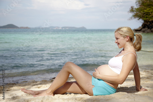 schwangere frau sitzt am strand