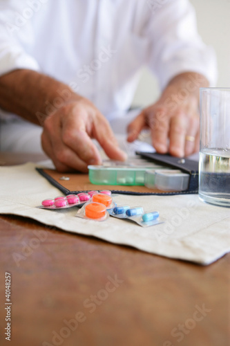 Old lady using pillbox to keep medicine organized