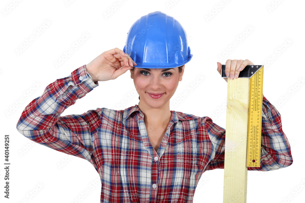 female apprentice looking pleased with ruler and hard hat female apprentice looking pleased with ruler and hard hat