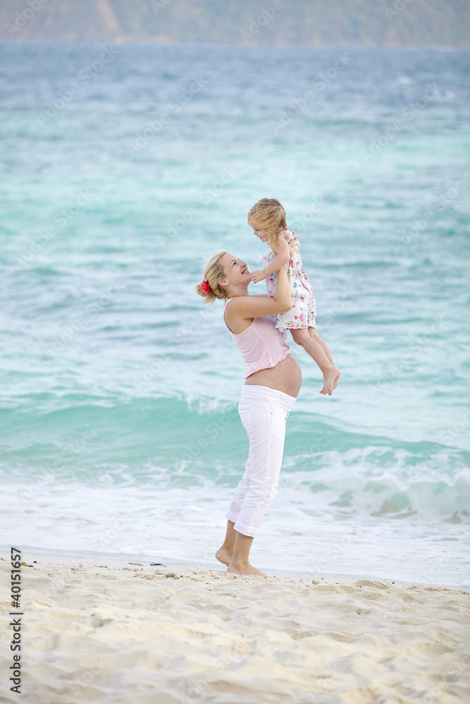 junge schwangere mutter mit ihrer tochter am strand junge schwangere mutter mit ihrer tochter am strand