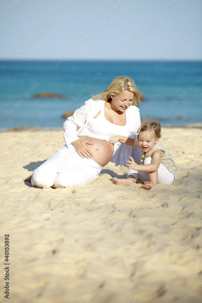 schwangere mutter spielt sand mit ihrer tochter schwangere mutter spielt sand mit ihrer tochter