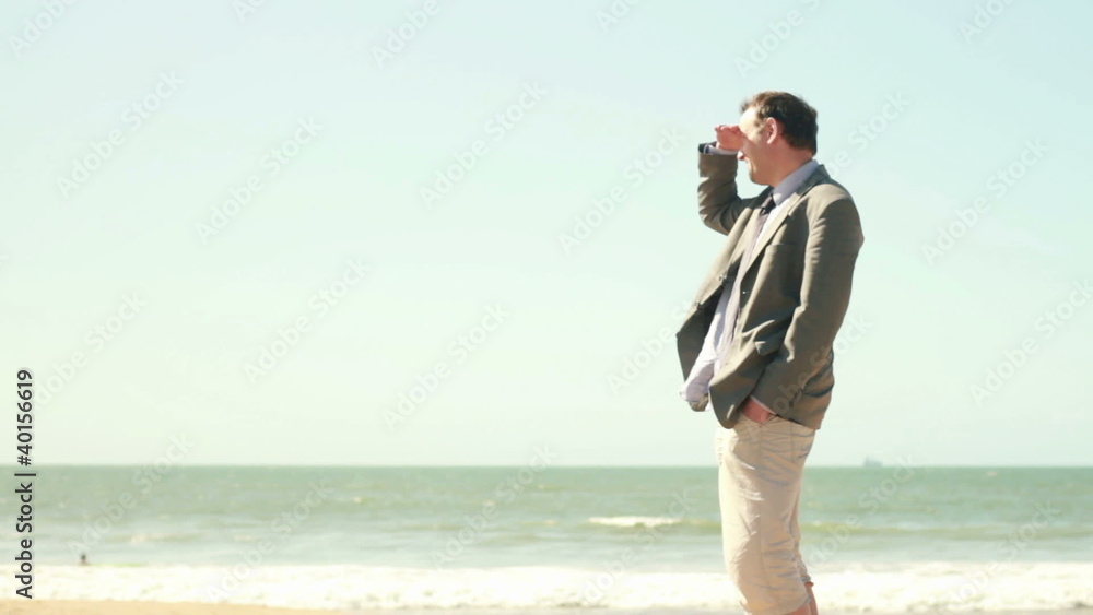 Businessman on the beach looking at the sea Businessman on the beach looking at the sea