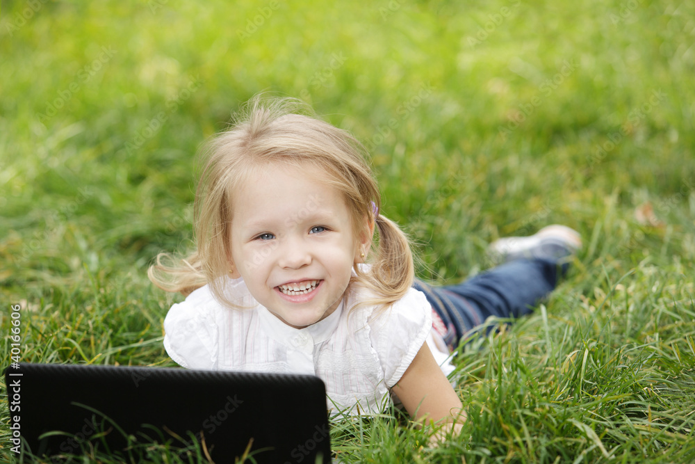 Little girl on the grass with laptop