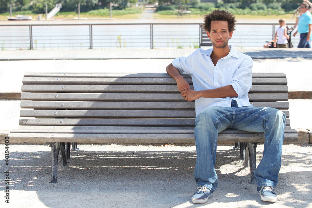 Young man sitting on a public bench Young man sitting on a public bench