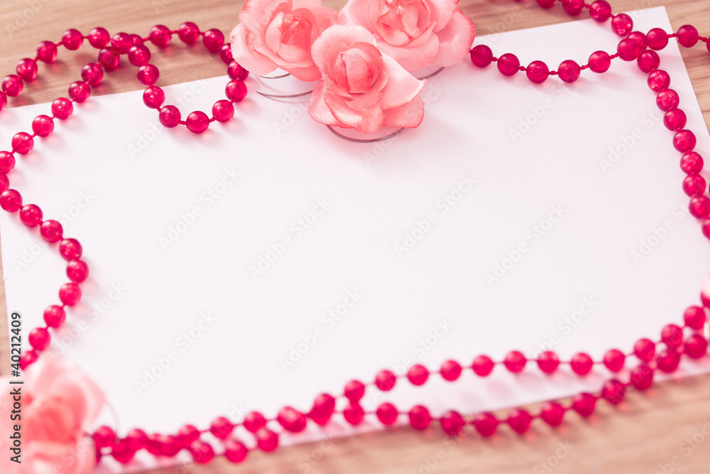 red beaded necklace and pink flower with empty card