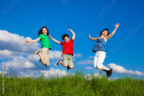 Active family - mother and kids running  jumping outdoor