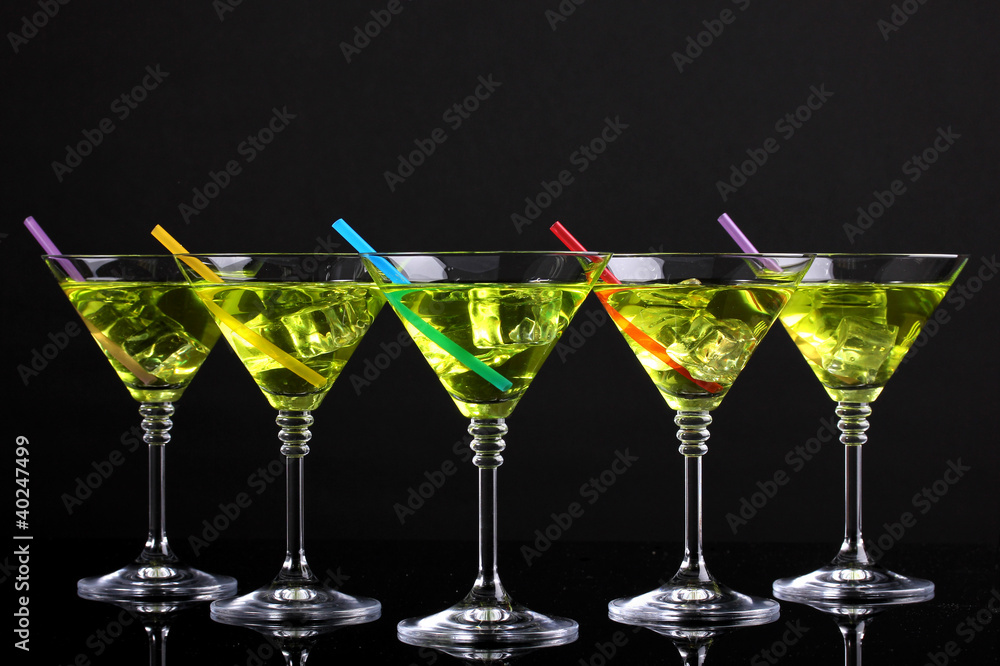 Yellow cocktail in martini glasses isolated on black Yellow cocktail in martini glasses isolated on black