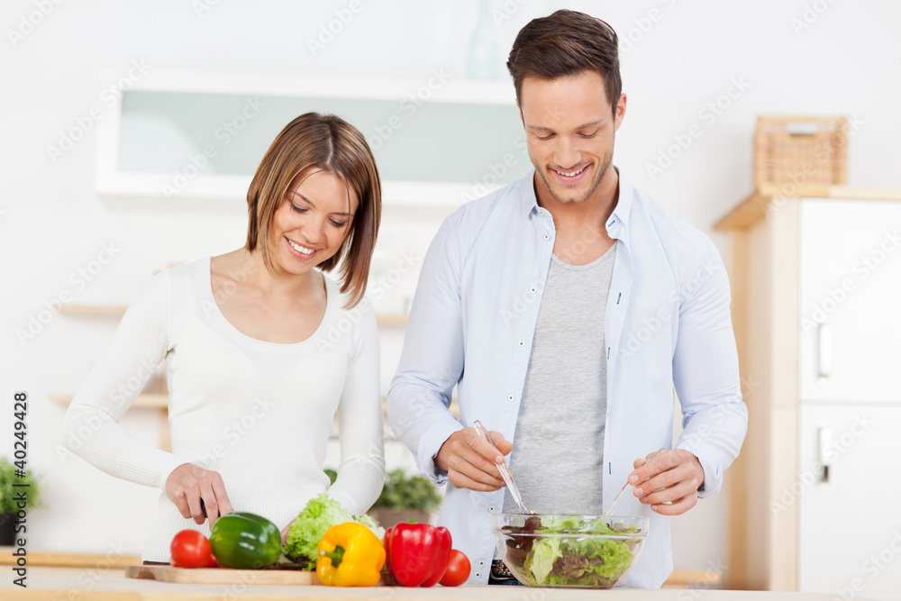 paar schneidet salat in der küche