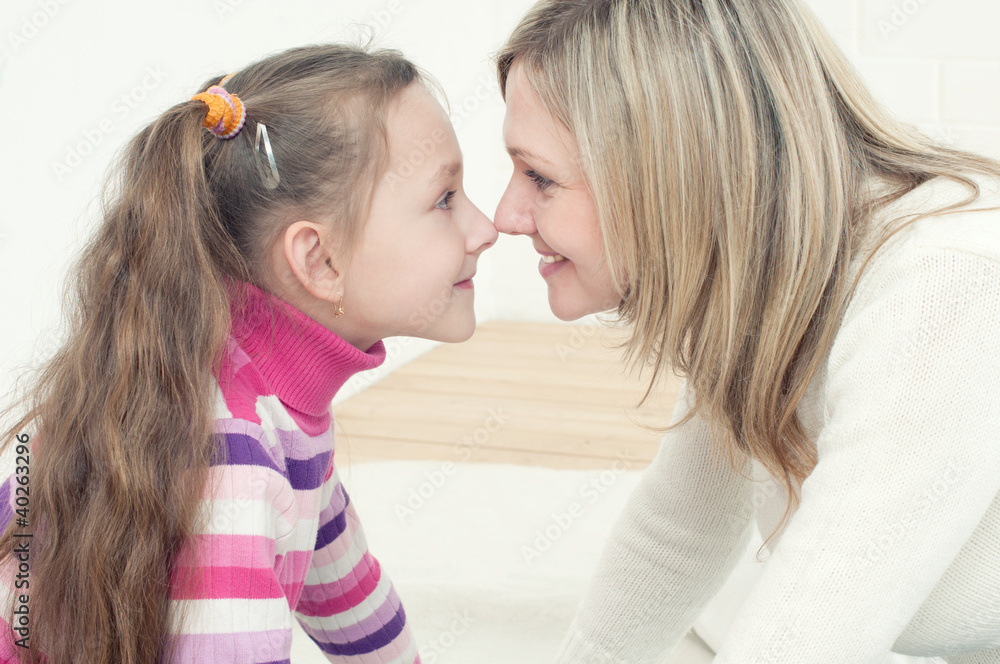 Happy young mother and her little daughter playing at home