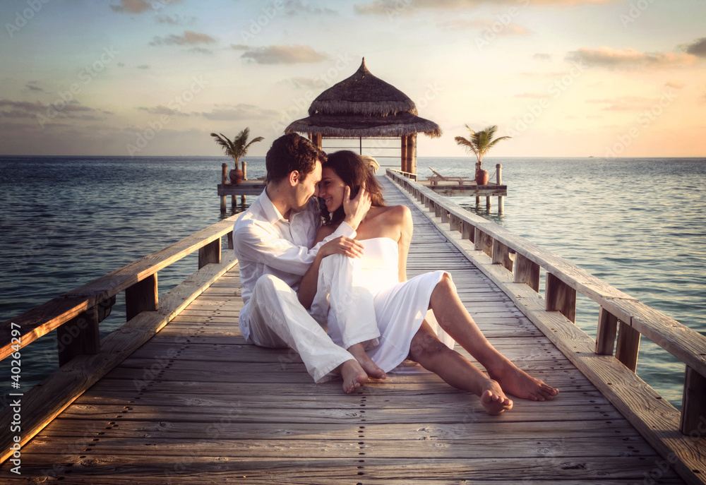 Sensual happy couple with white clothes on a pier (Maldives)