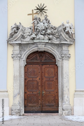 Entrance to a church. Wooden door, stone statuettes above it.