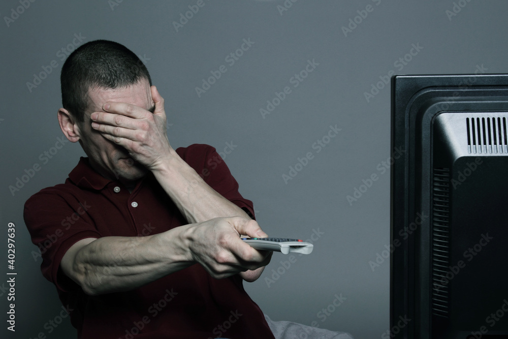 Naklejka premium homme horrifié regardant la télévision en zappant