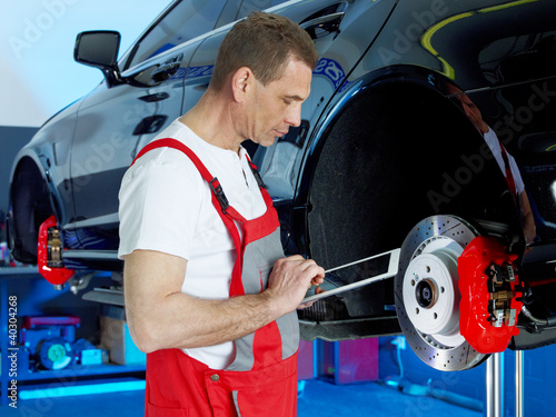 Master mechanic inspecting a break of a car with touchpad
