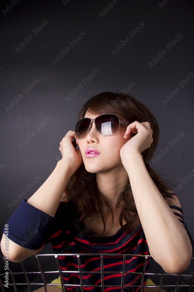female model pose with cool action with sunglasses on chair. female model pose with cool action with sunglasses on chair.