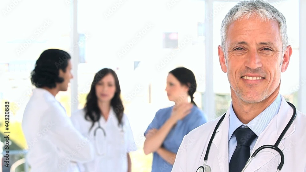 Smiling mature doctor standing in front of his team Smiling mature doctor standing in front of his team