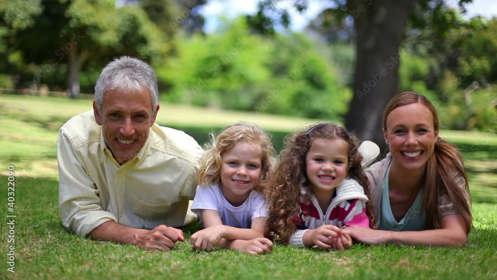Family posing together while lying on the grass Family posing together while lying on the grass