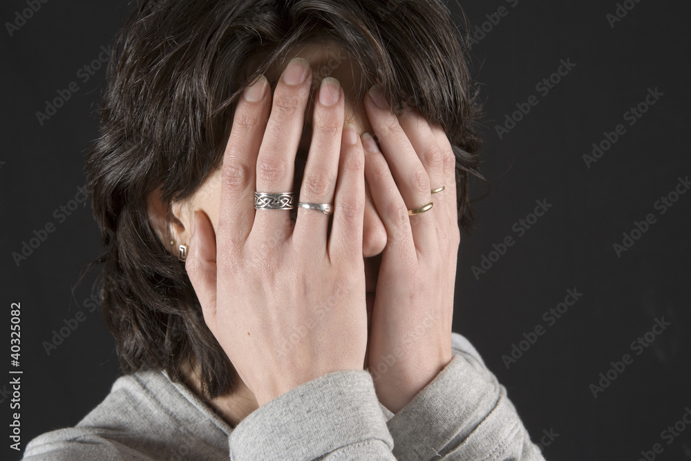 Mujer joven tapándose la cara con las manos. Mujer joven tapándose la cara con las manos.