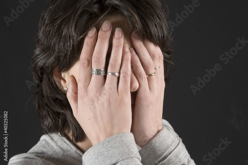 Mujer joven tapándose la cara con las manos.