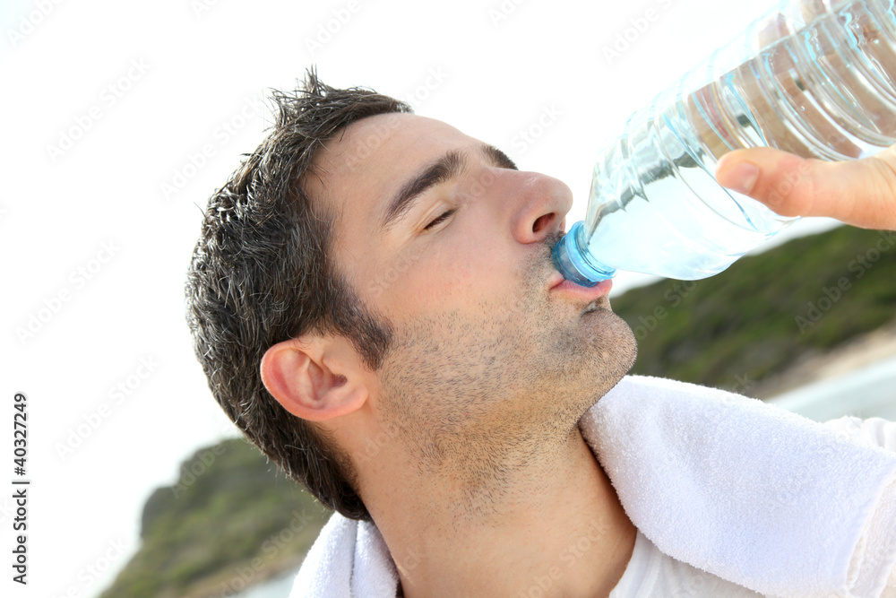 Jogger drinking water after exercising Jogger drinking water after exercising
