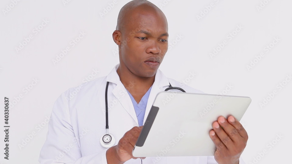 Serious doctor standing while holding a tablet pc Serious doctor standing while holding a tablet pc