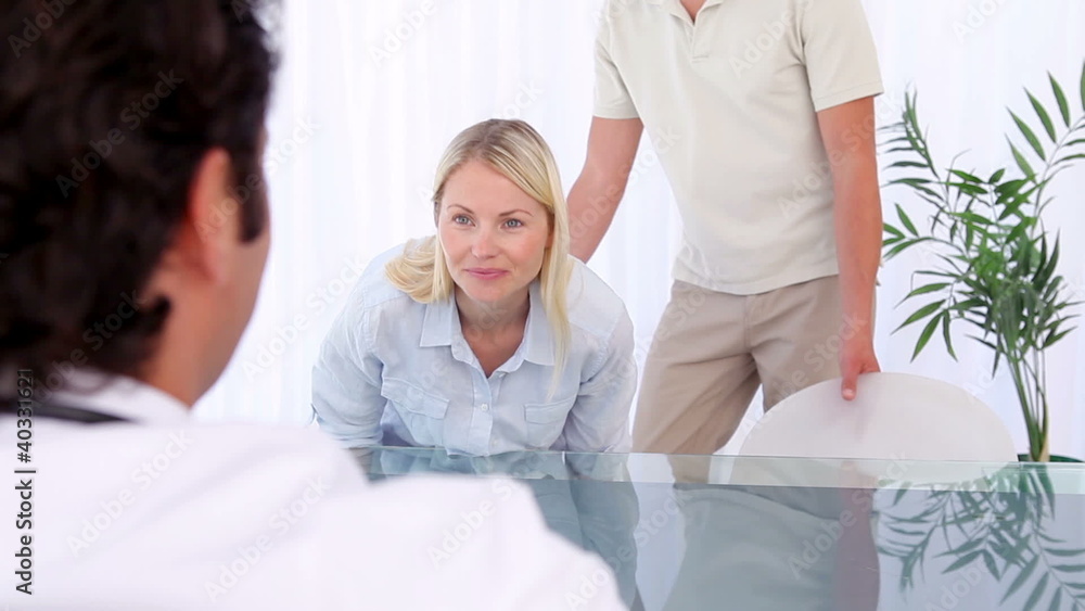 Peaceful couple sitting down in front of a doctor Peaceful couple sitting down in front of a doctor