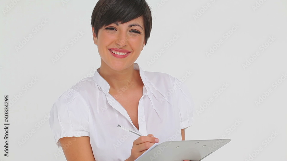 Businesswoman smiling while writing on a clipboard Businesswoman smiling while writing on a clipboard