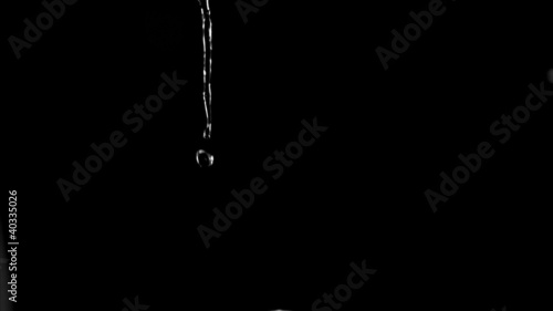 Very thin trickle of water in a super slow motion flowing 