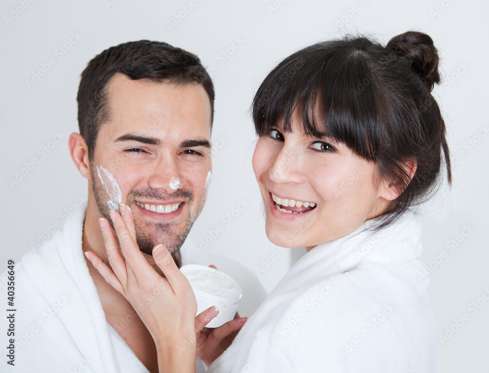 Playful young couple applying cream Playful young couple applying cream