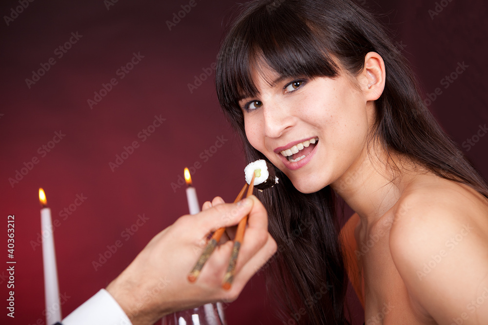 Obraz premium Young woman eating sushi in restaurant