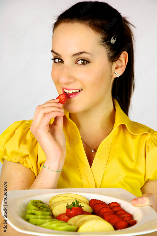 Female model with plate with fruit eating strawberry Female model with plate with fruit eating strawberry