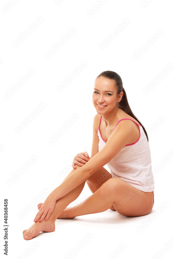 A beautiful woman applying cream on her legs, isolated on white A beautiful woman applying cream on her legs, isolated on white